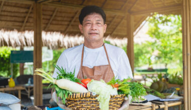 A happy farmer is standing and holding fruit vegetable basket from the farm.